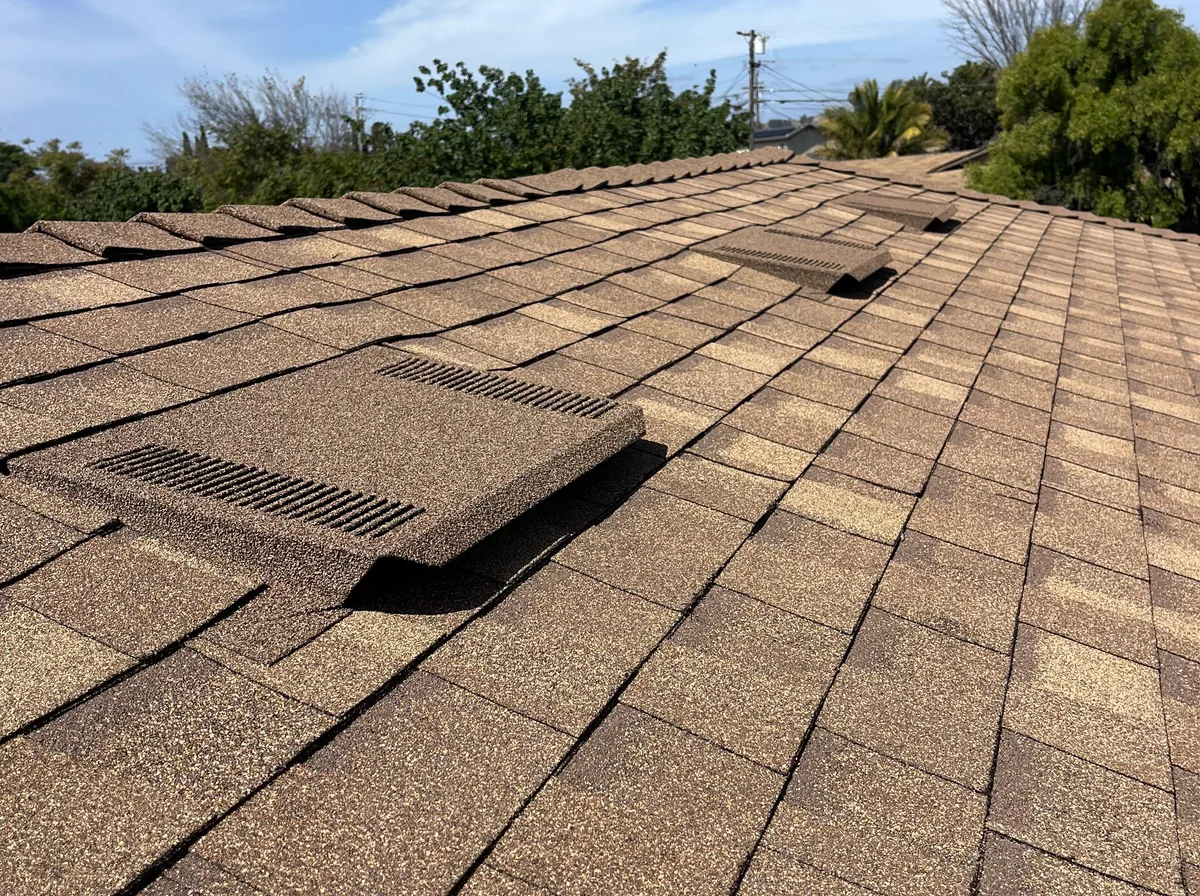 Two low-profile attic vents seated into the shingle courses on a Sonrise roof, running up the slope toward the ridge